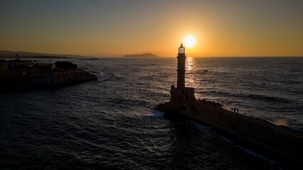 Sunset behind an old stone lighthouse in the Greek town of Chania, Crete