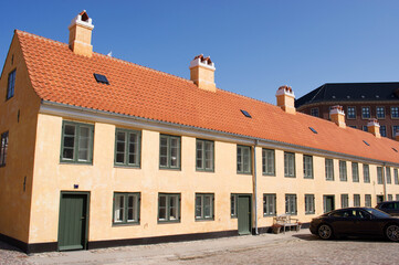 Traditional yellow terraced house with a red roof and a clear blue sky in Copenhagen in Denmark