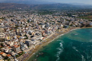 Fototapeta premium Aerial view of a busy beach in the popular resort town of Nea Chora in Chania, Crete (Greece)
