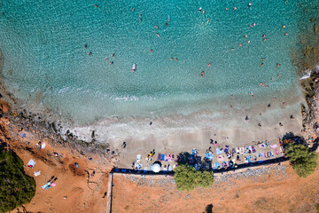 Top down aerial view of tourists on a small beach with crystal clear blue ocean on the island of Crete, Greece