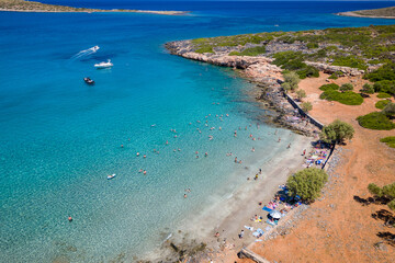 Fototapeta na wymiar Aerial view of a small beach and crystal clear ocean with swimmers on a hot summers day in Crete (Kolokitha)