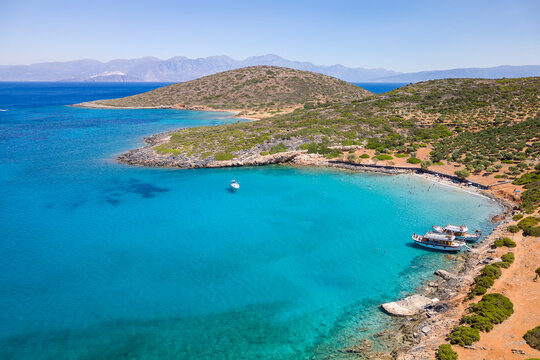 Aerial view of tourist boats and swimmers in crystal clear waters off a small beach (Kolokitha, Crete, Greece)