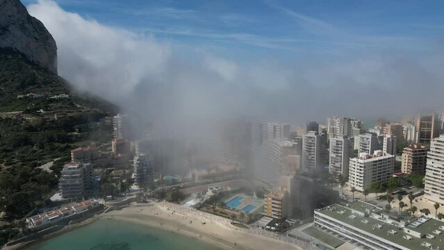 Drone shot view of Calpe and the Penon de Ifach in foggy and sunny day.