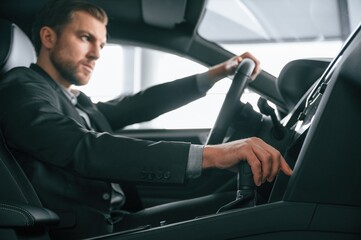 Test drive. Man in formal business clothes is sitting in the modern automobile