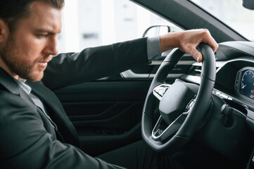 Test drive. Man in formal business clothes is sitting in the modern automobile