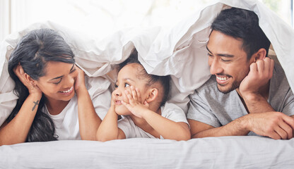 Home is wherever were together. Shot of a little girl lying between her mother and father on their bed.