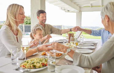 We have to do this more often. Shot of a family praying together before enjoying sunday lunch.