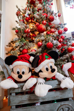 Coppia di Micky mouse vestiti da babbo natale e dietro loro un albero di Natale 