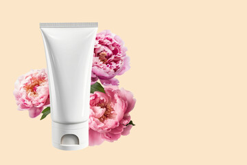 Mock-up of a white empty tube and natural pink peonies on a beige background. Top view, flat style. The concept of natural organic cosmetics.