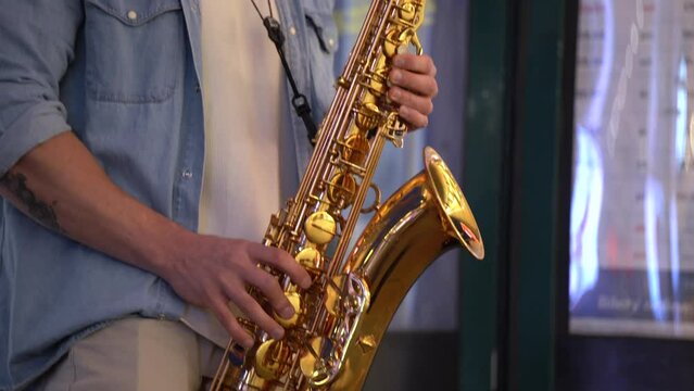 a musician's hands playing the saxophone on the street up close