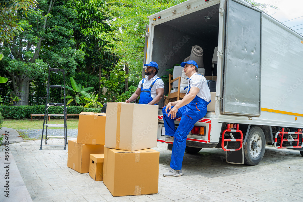 Poster removal company workers unloading boxes from truck into new home on moving day.