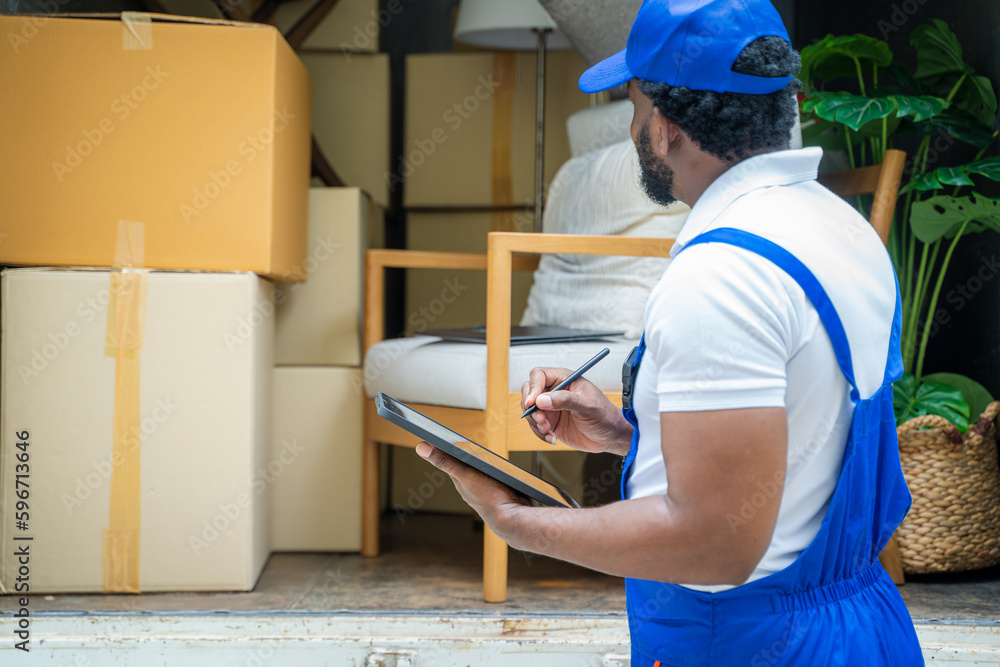 Poster moving company employee checks boxes in a small truck before sending them to the homeowner.