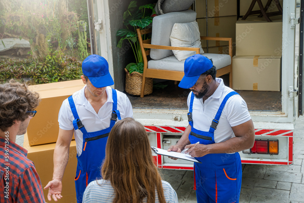 Poster happy couple with moving boxes at new house,moving company employee checks boxes in a truck before s