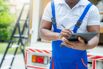 Delivery man checking list on clipboard near car before sending them to the homeowner.
