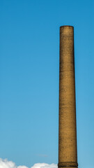 Old chimney of a farbrick with blue sky in background