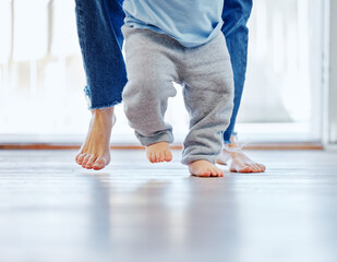 Soon hell be walking on his own. Cropped shot of an unrecognizable little boy learning to walk with the help of his mother at home.