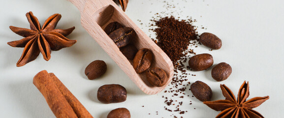 Banner with roasted coffee beans and ground coffee in scoop with spices, cinnamon stick, star anise