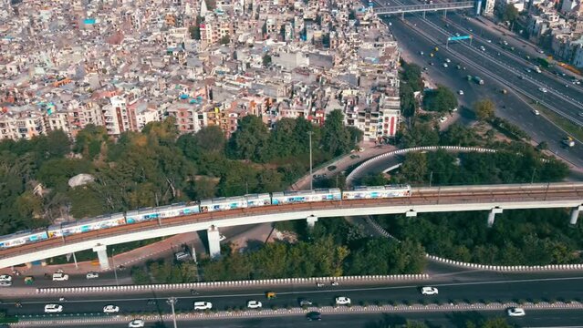 Aerial view of Indian capital and metropolitan city of New Delhi, India. Drone shot of metro rail moving above 8-lane highway and flyover bridges in Delhi. Roads of developing India. Indian Cityscape 