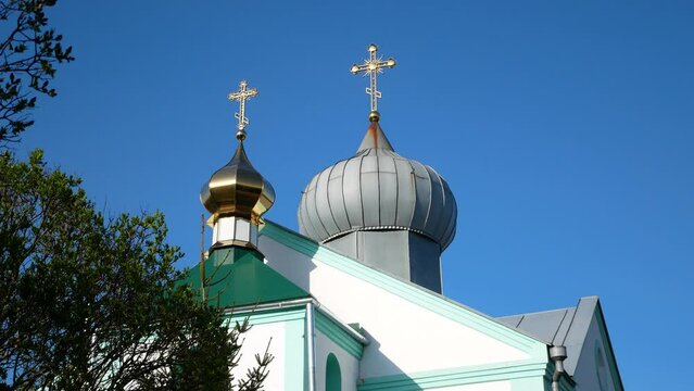An Orthodox church with gold and gray domes and shiny golden crosses on them against the blue sky. Orthodoxy. Church of the Moscow Patriarchate in Ukraine. Orthodox holidays