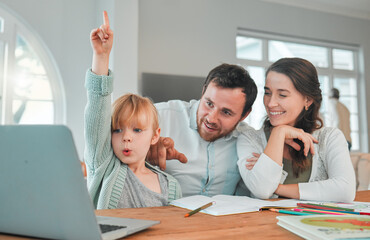 Adorable little caucasian girl sitting at table using a wireless laptop and doing homework while her mom and dad helps her. Beautiful happy young woman smiling and teaching her daughter at home while