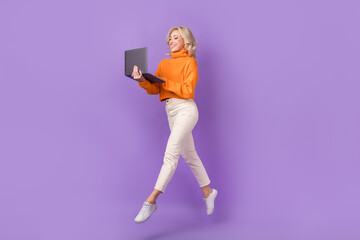 Full length profile photo of active pretty person jumping use netbook isolated on violet color background