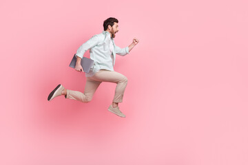 Fototapeta na wymiar Full length photo of impressed funky man wear turquoise shirt holding gadget running empty space isolated pink color background