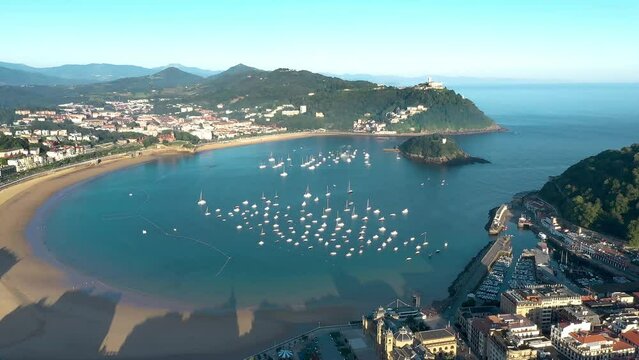 San Sebastian - Donostia - SPAIN. Aerial view of the old town center. View of La concha Beach and Bay area. Drone going backward above the city center. Rooftops of San Sebastian. Sunrise warm colours 