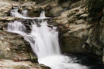 Fototapeta na wymiar Autumn waterfall in a small rocky river. Motion blur.