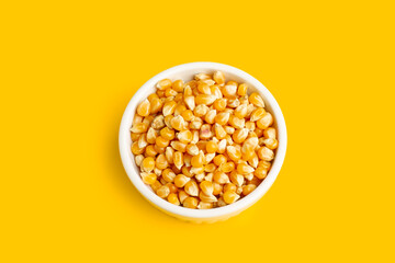 Granos de maíz dentro de un cuenco de cerámica blanca sobre un fondo amarillo brillante liso y aislado. vista superior y de cerca. Copy space