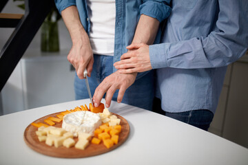 Beautiful young couple, loving man and woman preparing breakfast together in morning in kitchen. Close-up of men's hands. Love, relationship, family, emotions, lifestyle, support and care concept