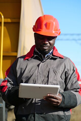 African american railway man with tablet computer at freight train terminal