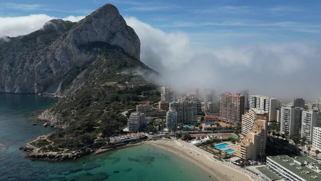 Aerial footage.Mystical Calpe.Explore the enchanting town of Calpe and the iconic Penon de Ifach on unique day where the mist and sunshine blend together. 