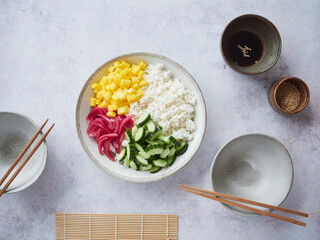 colorful homemade poke bowl with rice, mango, cucumber and pickled red onion. Ready to serve beside bowl with soy sauce