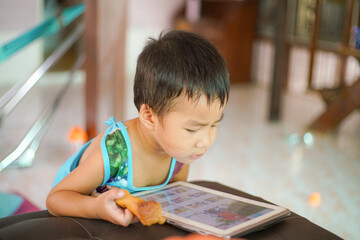 Adorable little boy playing tablet computer watching cartoon