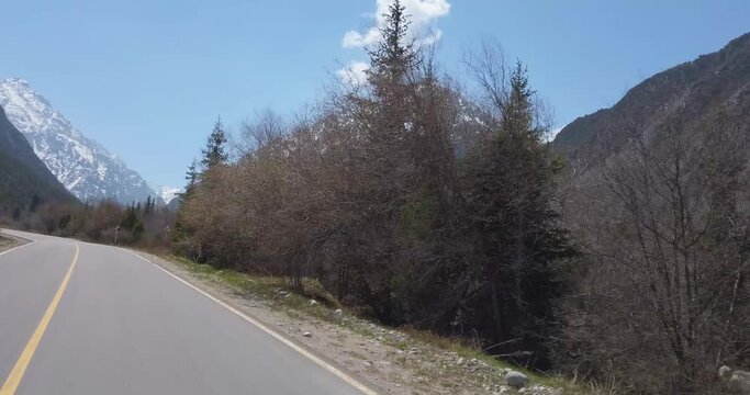 Road among snowy mountains in spring