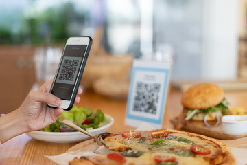 Woman use smartphone to scan QR code to pay in cafe restaurant with a digital payment without cash. Choose menu and order accumulate discount. E wallet, technology, pay online, credit card, bank app.