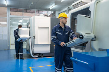 Male engineer operating cnc machine in control panel at factory. Man technician in uniform and...