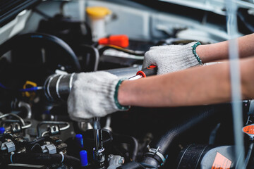 Close-up of a female repairman's hand. Car care and maintenance, hands-on car mechanic using a wrench to fix the car engine problem. Audit and Service Concepts