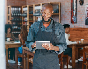 Young african american businessman wearing a apron working in a retail store using a digital tablet...