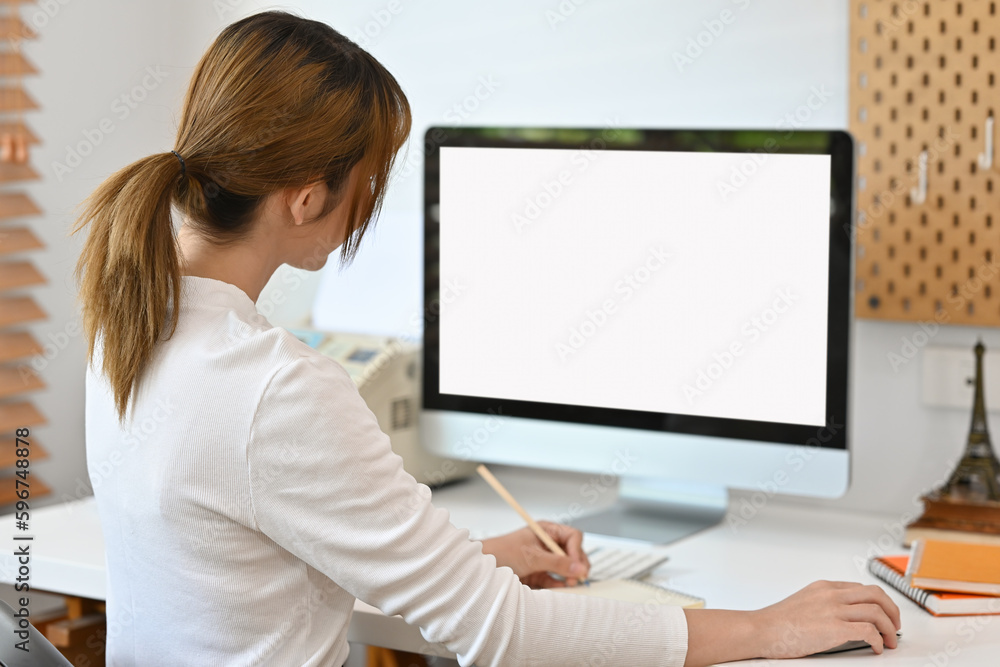 Aufkleber rear view with female office worker using computer at her desk, empty of device screen.