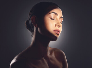 Beauty is the light in the heart. Studio shot of a beautiful young woman posing with light beam against her face.