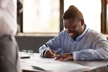 African Business Man Signing Paper Contract With Manager In Office