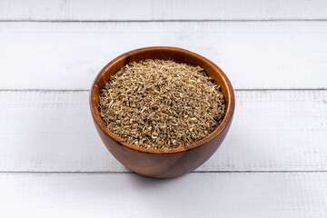 Anise seed on wooden bowl. 45 degrees studio shoot isolated on light wooden background.