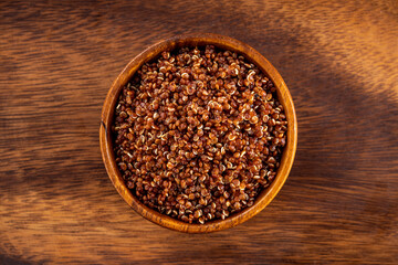 Cooked red quinoa bowl. Up view studio shoot on wooden background.