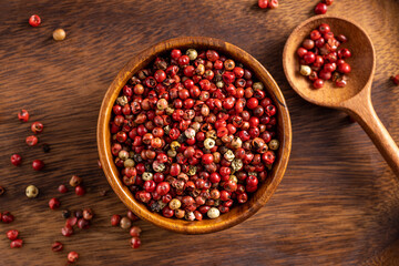 Red pepper seeds bowl and wooden rustic spoon. Up view studio shoot on wooden background.