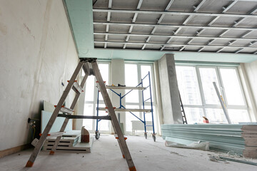 Workers are installing plasterboard (drywall) for gypsum walls in apartment is under construction,...