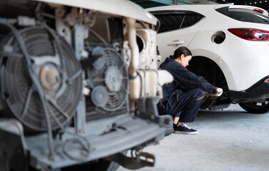 A female mechanic checking the condition of a car's brake discs and the condition of the tires that have been used for a while
