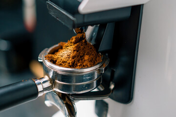 Professional barista worker use grinder machine to grind fresh coffee beans for make hot beverage at coffee cafe shop