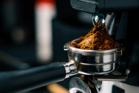 Professional barista worker use grinder machine to grind fresh coffee beans for make hot beverage at coffee cafe shop