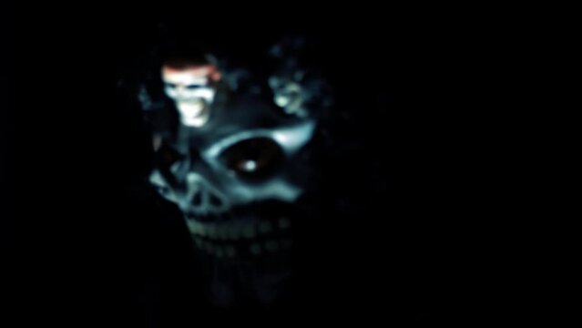 Shot of a man wearing a dark scary Halloween mask, celebrating Halloween with flame or fire lighting his face, HD footage.